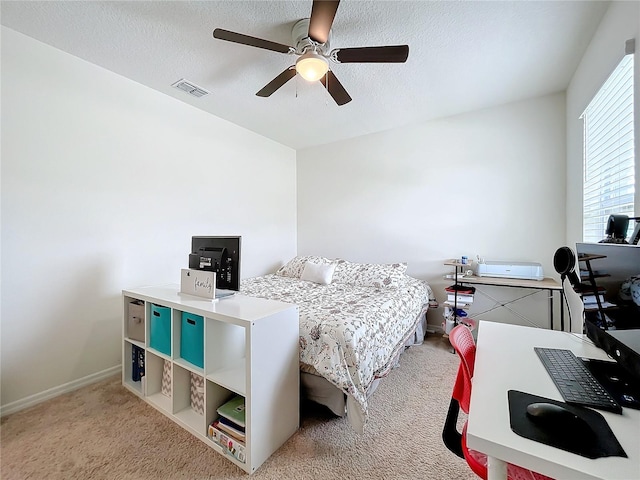 carpeted bedroom featuring ceiling fan and a textured ceiling