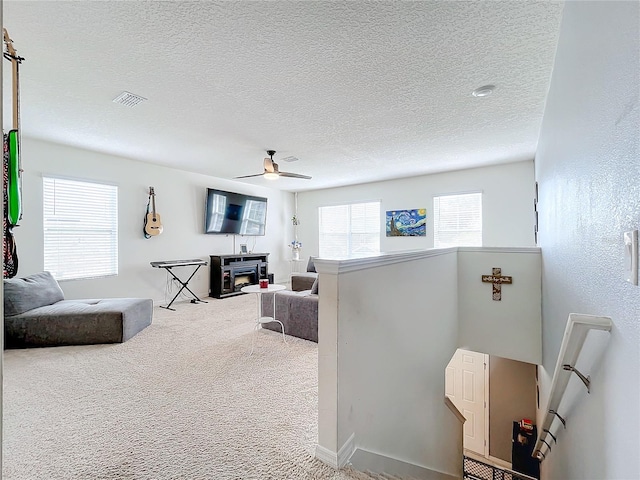 carpeted living room featuring a textured ceiling and ceiling fan