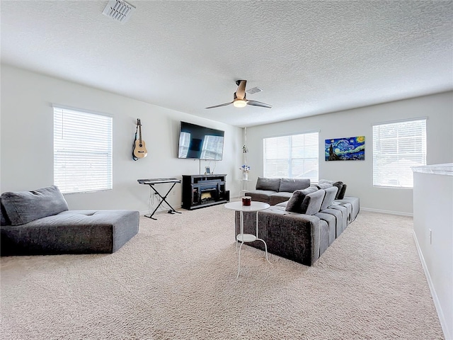 carpeted living room with ceiling fan, a textured ceiling, and plenty of natural light