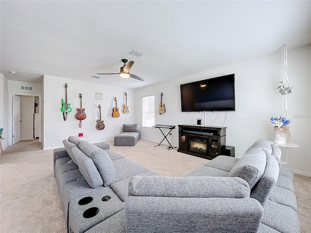 living room with light carpet, ceiling fan, a fireplace, and a textured ceiling