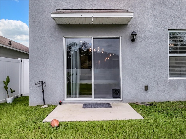 view of exterior entry featuring a patio and a yard