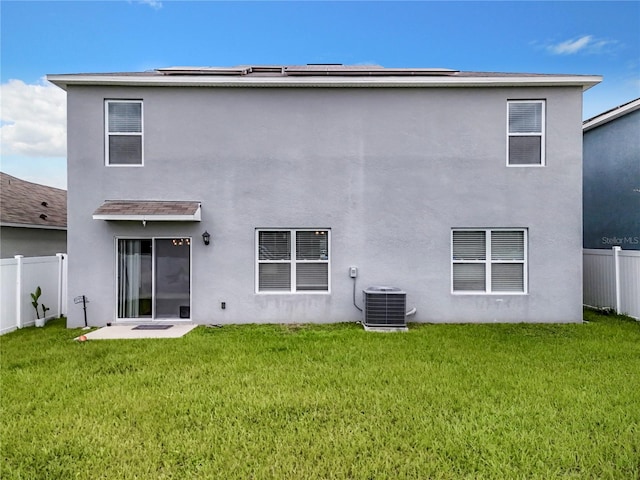 back of house with central AC unit and a yard