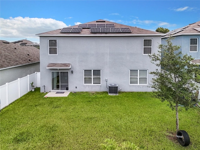 rear view of house with solar panels, a yard, a patio, and central AC