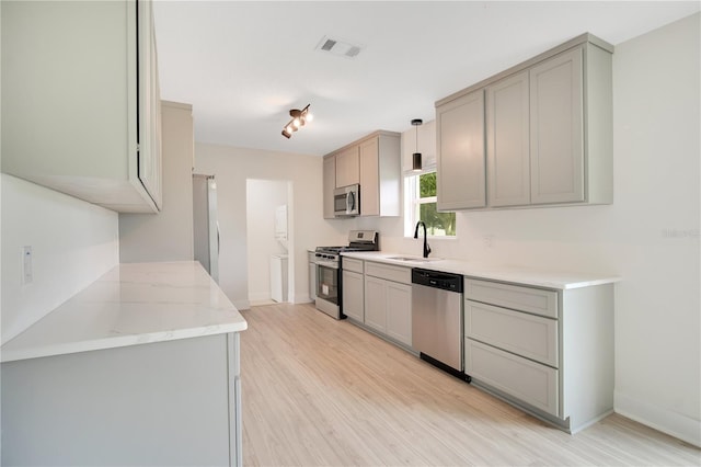 kitchen featuring pendant lighting, sink, light wood-type flooring, and stainless steel appliances