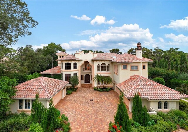 9164 Point Cypress Dr, Orlando, FL 32836 - mediterranean / spanish house featuring stucco siding, decorative driveway, a tiled roof, and a chimney