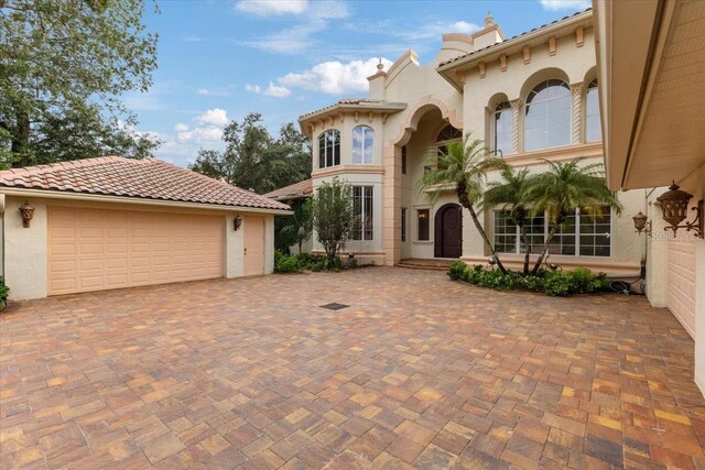 9164 Point Cypress Dr, Orlando, FL 32836 - mediterranean / spanish home featuring a garage, stucco siding, decorative driveway, and a tile roof