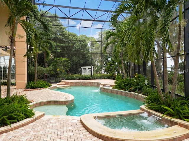 view of pool with pool water feature, glass enclosure, and a patio area