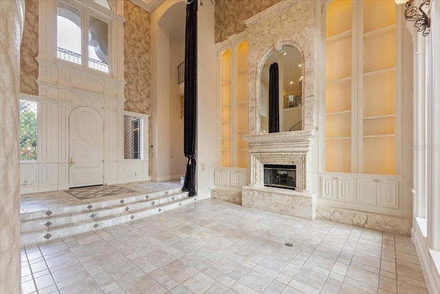 interior space with a high ceiling, a large fireplace, and built in shelves