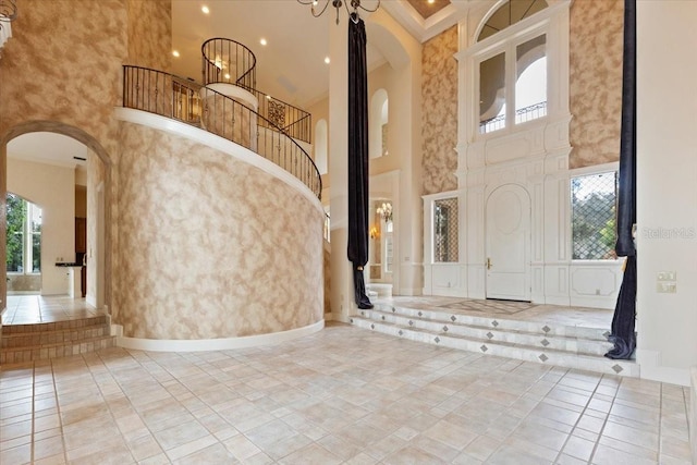 tiled entryway with an inviting chandelier and a towering ceiling