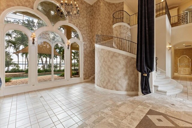 9164 Point Cypress Dr, Orlando, FL 32836 - tiled foyer entrance featuring a towering ceiling, a chandelier, stairway, and arched walkways