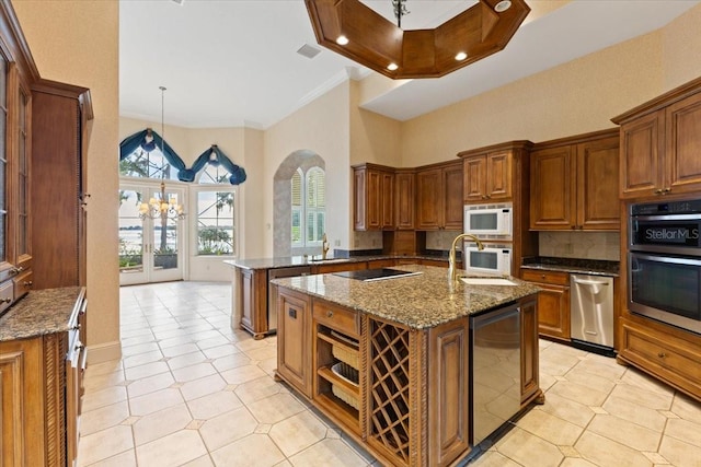 kitchen with dark stone countertops, an island with sink, kitchen peninsula, stainless steel appliances, and ornamental molding