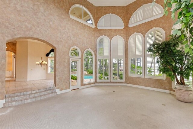9164 Point Cypress Dr, Orlando, FL 32836 - unfurnished living room featuring a chandelier, carpet floors, arched walkways, and a towering ceiling