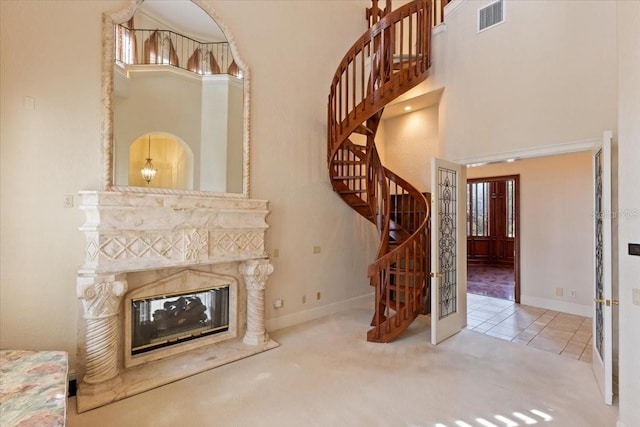 9164 Point Cypress Dr, Orlando, FL 32836 - unfurnished living room with a high ceiling, stairs, carpet flooring, a high end fireplace, and tile patterned flooring