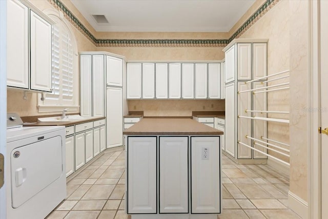 kitchen with a kitchen island, white cabinetry, and washer / dryer