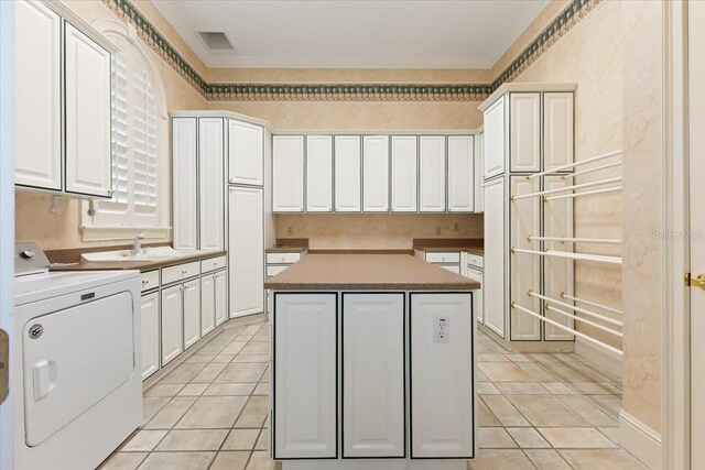 9164 Point Cypress Dr, Orlando, FL 32836 - kitchen featuring a center island, white cabinetry, light tile patterned floors, and ornamental molding