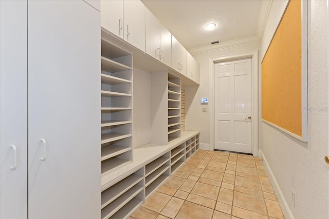 mudroom featuring a textured ceiling, ornamental molding, and light tile patterned floors