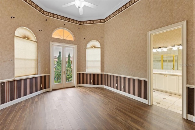 empty room with wood-type flooring, wood walls, ceiling fan, and french doors