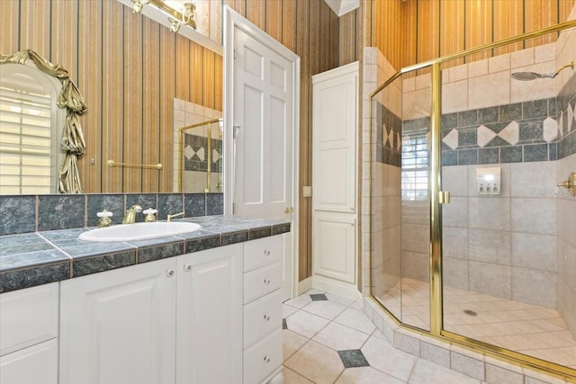 bathroom featuring vanity, backsplash, a shower with door, and tile patterned floors