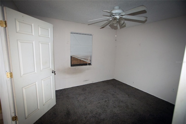 empty room with ceiling fan, a textured ceiling, and dark colored carpet