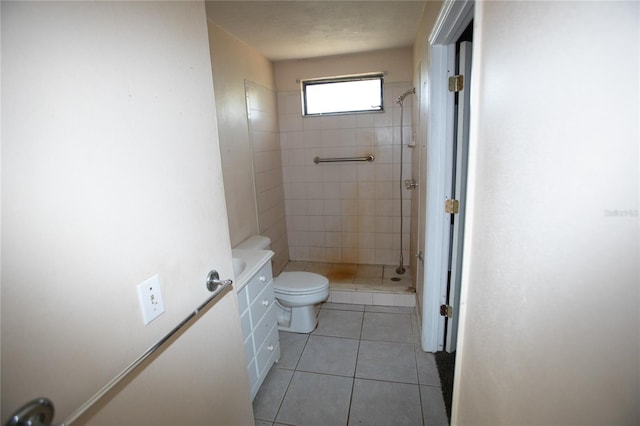 bathroom with a tile shower, tile patterned flooring, and toilet