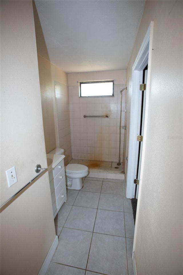 bathroom featuring tiled shower, tile patterned flooring, vanity, and toilet