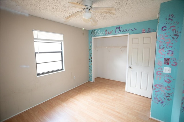 unfurnished bedroom with ceiling fan, light wood-type flooring, a textured ceiling, and a closet