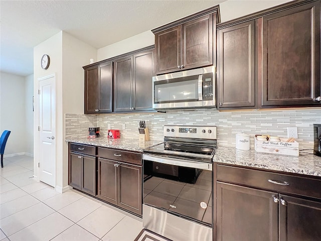 kitchen featuring stainless steel appliances, light stone counters, dark brown cabinetry, and backsplash