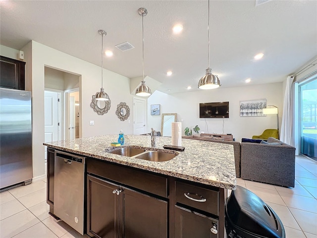 kitchen featuring dark brown cabinetry, light stone counters, sink, decorative light fixtures, and appliances with stainless steel finishes