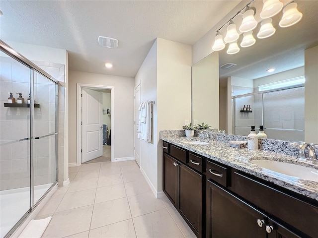 bathroom featuring tile patterned flooring, a textured ceiling, walk in shower, and vanity