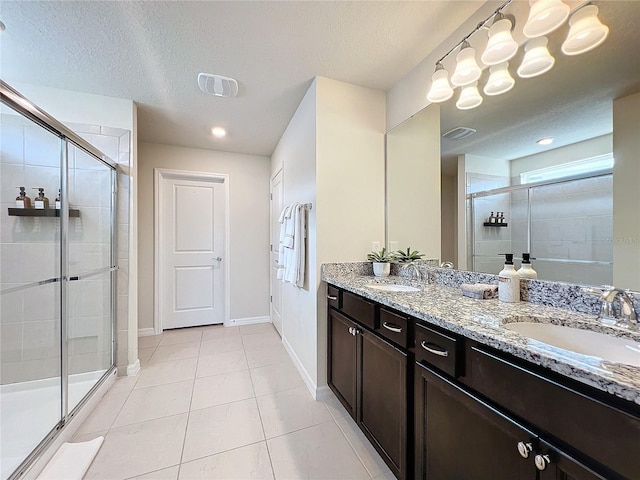 bathroom featuring vanity, a textured ceiling, an enclosed shower, and tile patterned floors