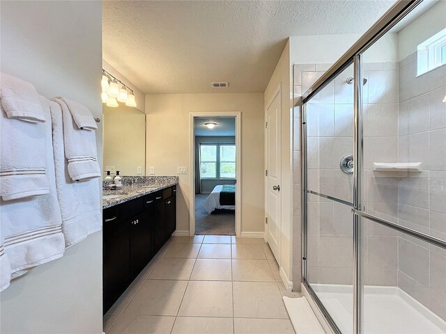 bathroom with tile patterned flooring, a textured ceiling, walk in shower, and vanity