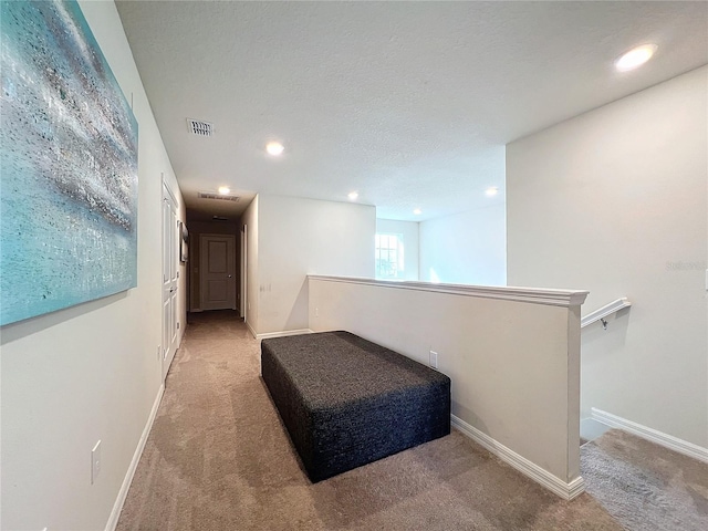 hallway with a textured ceiling and carpet floors