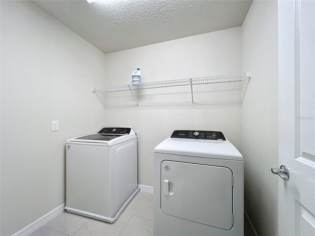 laundry area featuring a textured ceiling and washing machine and dryer