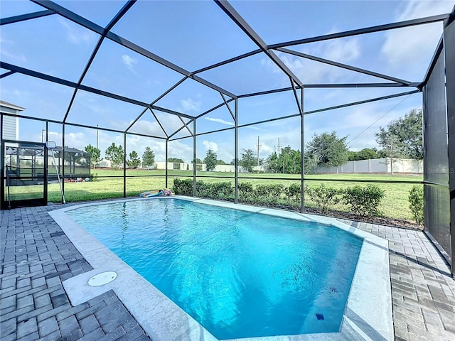 view of pool with glass enclosure, a patio area, and a yard