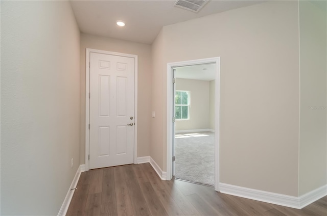 hallway featuring wood finished floors, baseboards, and visible vents