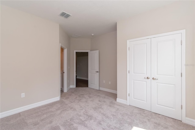 unfurnished bedroom featuring a closet, carpet floors, visible vents, and baseboards