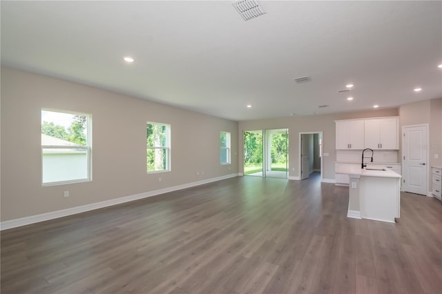 unfurnished living room with a sink, dark wood-style floors, baseboards, visible vents, and recessed lighting