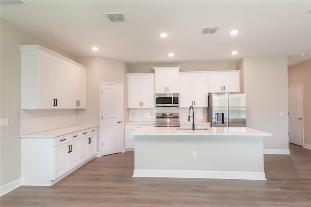kitchen featuring a center island with sink, a sink, stainless steel appliances, and visible vents