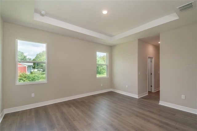 empty room featuring visible vents, baseboards, recessed lighting, a raised ceiling, and dark wood-type flooring