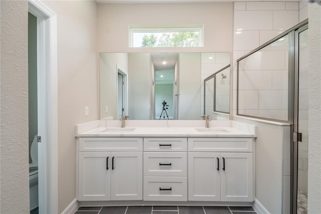 bathroom featuring baseboards, double vanity, a sink, and a shower stall