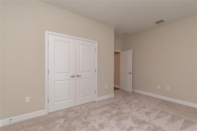 unfurnished bedroom featuring baseboards, visible vents, and light colored carpet