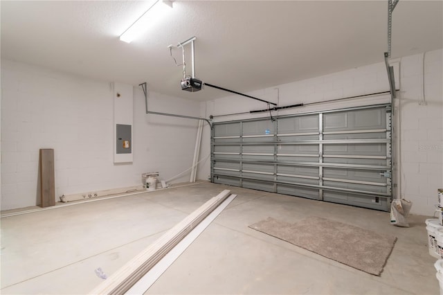 garage with concrete block wall, electric panel, and a garage door opener