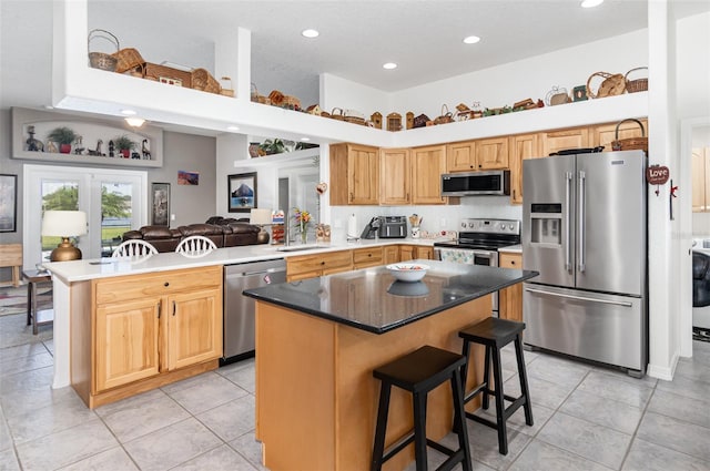 kitchen featuring a kitchen breakfast bar, a kitchen island, stainless steel appliances, a high ceiling, and sink