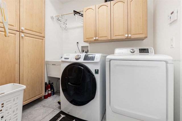 washroom featuring washer and clothes dryer, cabinets, and light tile patterned floors