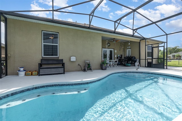 view of swimming pool featuring glass enclosure, ceiling fan, and a patio