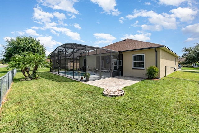 rear view of property featuring glass enclosure, a yard, a patio, and a fenced in pool