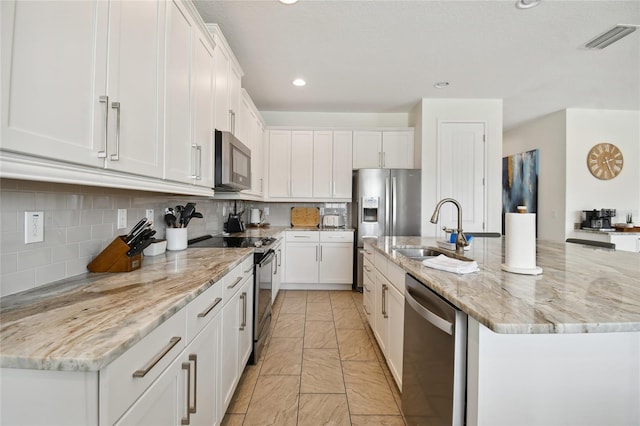 kitchen featuring appliances with stainless steel finishes, a kitchen island with sink, and white cabinetry