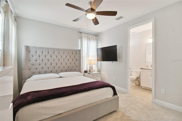 bedroom featuring ceiling fan, light colored carpet, and ensuite bath