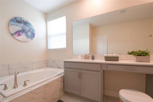 bathroom with vanity, a relaxing tiled tub, and toilet