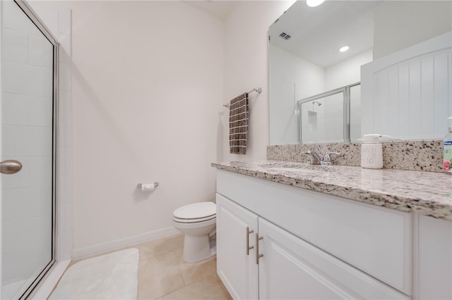 bathroom with tile patterned flooring, a shower with door, vanity, and toilet